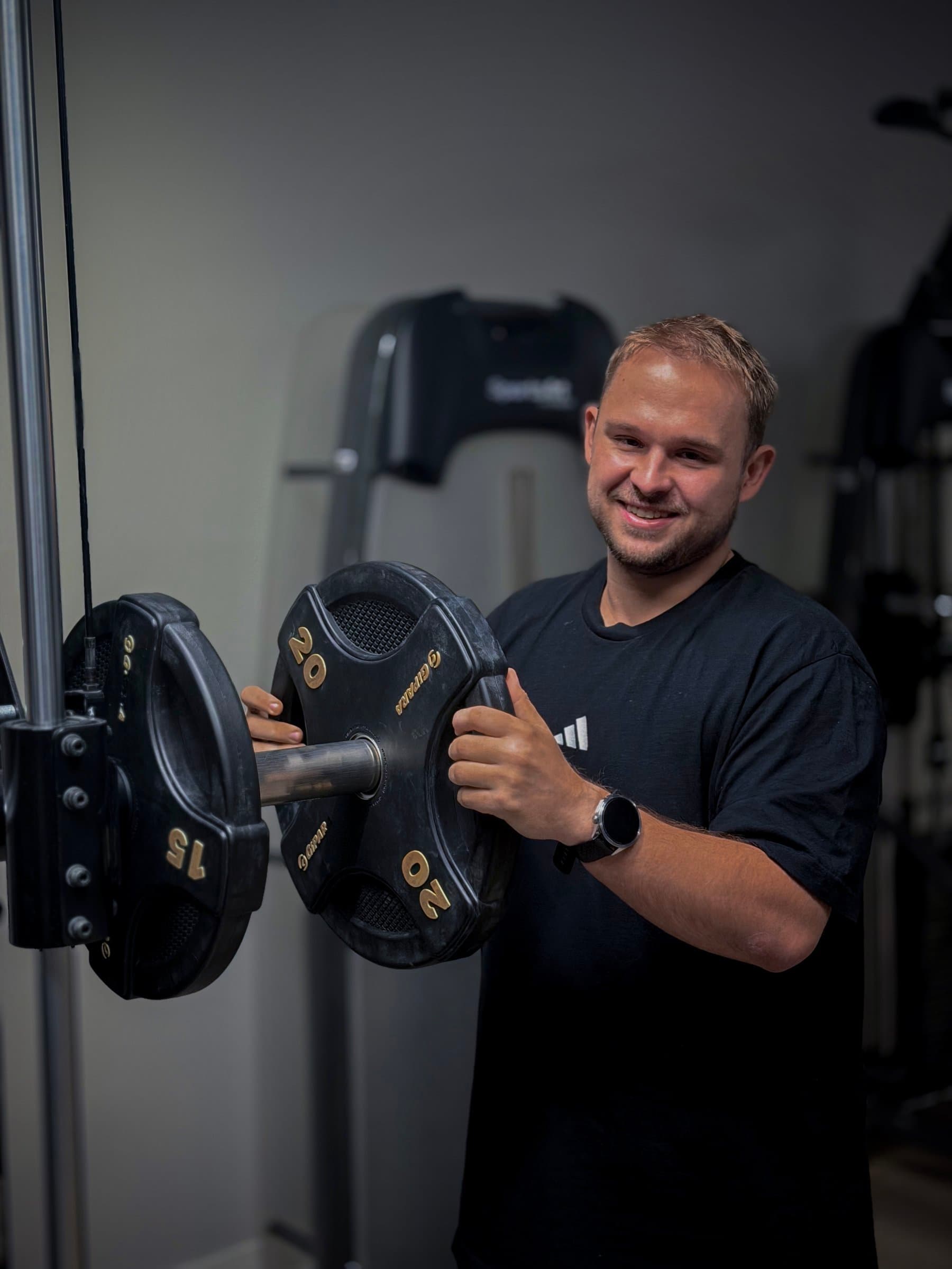 Dawid Marczak zakłada obciążenie na sztangę podczas treningu we Wrocławiu